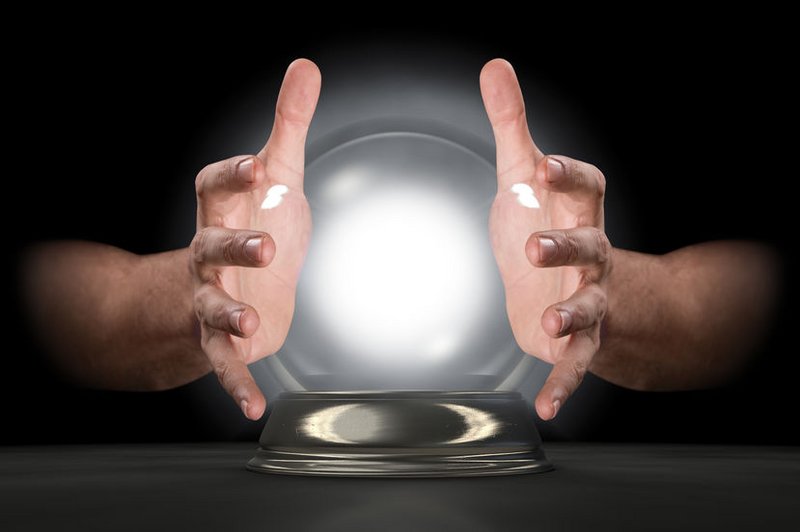 Twee handen van de paragnost, rond een glazen bol die licht geeft.