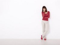 Een hooggevoelige vrouw leunt tegen een witte muur, ver weg. 