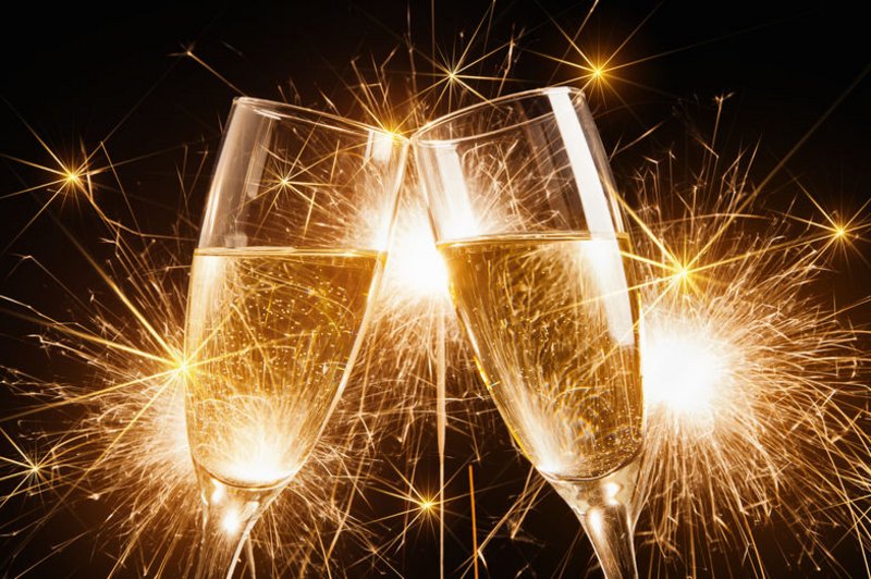 Twee glazen champagne proosten op de goede voornemens, met vuurwerk op de achtergrond