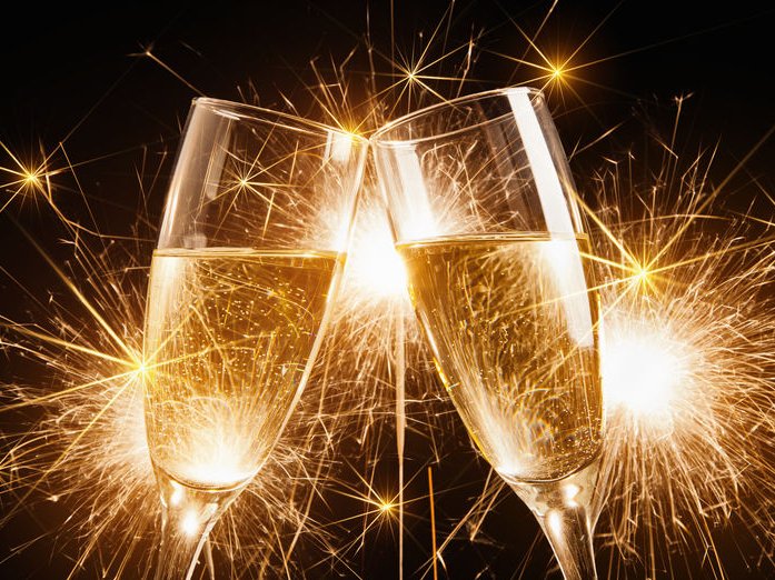Twee glazen champagne proosten op de goede voornemens, met vuurwerk op de achtergrond