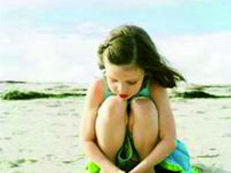 Een klein meisje speelt helemaal alleen op het strand. Ze ziet er verdrietig en eenzaam uit.