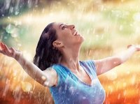 Een vrouw staat helemaal blij te genieten van de regen