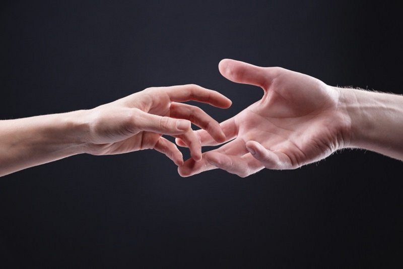 Een zwarte achtergrond met twee handen die elkaar loslaten, omdat het vertrouwen weg is na vreemdgaan. Of reiken ze juist naar elkaar omdat ze samen verder willen?