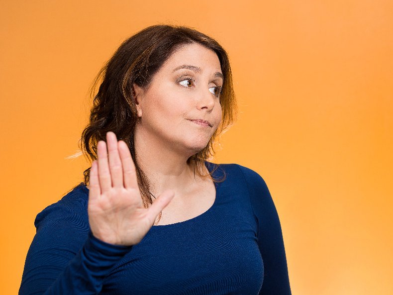 Een vrouw maakt een verwijtend en afwerend gebaar met haar hand.