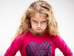 Een klein meisje kijkt heel erg boos, ze is het niet eens met haar opvoeding