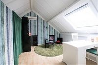 De praktijkruimte is een ruime lichte zolderkamer, met groentinten op de muren, en groot dakraam. Een rond groen kleed onder de behandelstoel symboliseert het energieveld.