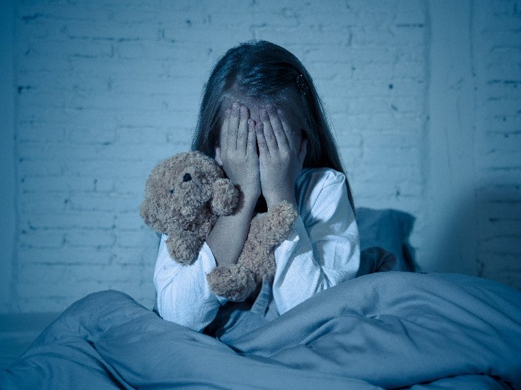 Een kindje is bang voor geesten en zit met haar handen voor haar ogen in bed. Ze wil de geesten niet meer zien.