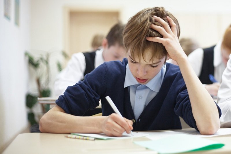 Een jongen zit geconcentreerd zijn examen te maken
