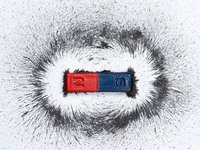 Een magneet met een ring van ijzeldeeltjes er ruim omheen. je ziet zo precies hoe groot het magnetische veld is.