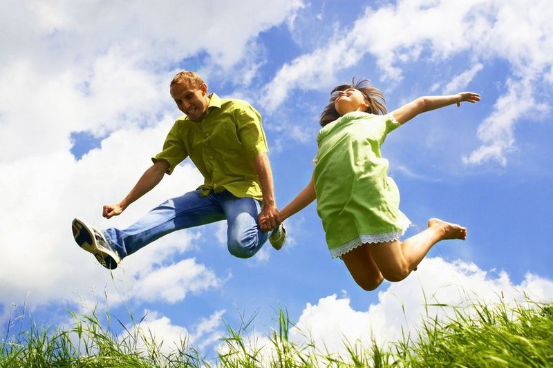Een man en een vrouw springen vol energie de lucht in.