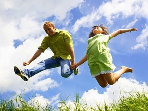 Een man en een vrouw springen vol energie de lucht in.