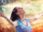Een vrouw staat blij te genieten van de regen. Door te visualiseren kan je positief blijven