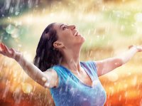 Een vrouw staat helemaal blij te genieten van de regen