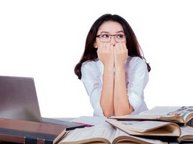 Een vrouw met examenvrees voelt een blokkade en zit heel angstig achter haar laptop.