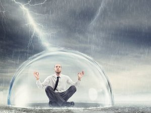 Een man zit veilig en rustig, beschermd tegen onweer en overprikkling, onder een glazen stolp