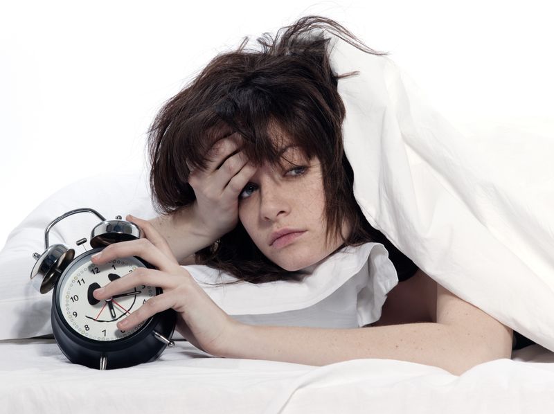 Een hooggevoelige vrouw wordt doodmoe wakker met een wekker in haar hand